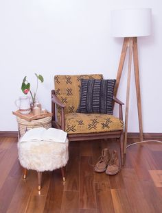 a chair and footstool in front of a lamp on a wooden floor next to a white wall