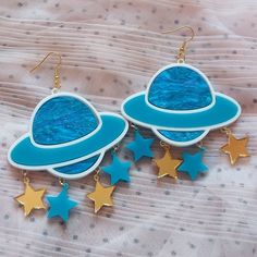 *These out of this world Saturn earrings are made with so many fun and interesting details. *They were laser cut with white, detailed blue, teal, and gold acrylic. *Three star charms are attached under each Saturn piece.   *The pieces were then added to hypoallergenic gold tone earring hooks. **These earrings can be made with sterling silver hooks, regular posts, or wrap around hooks -- if you prefer any of these options just let us know in the notes to seller section during checkout! CONTACT: *Feel free to contact BC with any questions or requests via Etsy conversations or bonescouture [!at] gmail.com SHIPPING: *All packages are wrapped in tissue paper, contain a BC card, and various fun freebies! Receipts are only included if specified. *We are happy to include a personal message for you Fun Blue Nickel-free Earrings, Whimsical Blue Nickel-free Earrings, Playful Blue Drop Earrings Jewelry, Blue Themed Earrings For Gift, Themed Blue Earrings For Gifts, Themed Blue Earrings For Gift, Blue Fun Dangle Jewelry, Fun Blue Dangle Jewelry, Fun Blue Nickel-free Jewelry