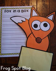 a fox in a box cut out next to a piece of paper on a wooden table