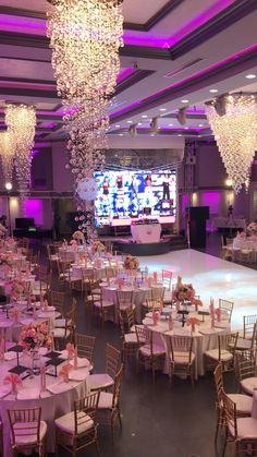 a banquet hall with tables and chairs set up for a formal function in front of a large television screen