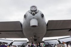 the nose of an airplane with people standing around it and onlookers in the background