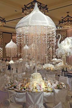 an elaborate chandelier hangs from the ceiling in a banquet room with white linens