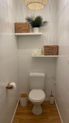 a white toilet sitting in a bathroom next to a shelf filled with baskets and candles