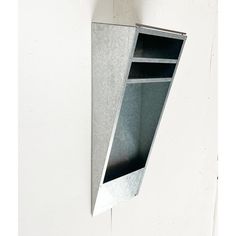 a metal shelf mounted to the side of a wall with an open section on it