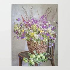 a basket filled with lots of flowers sitting on top of a wooden chair next to a wall