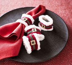 a black plate topped with red napkins and santa hats