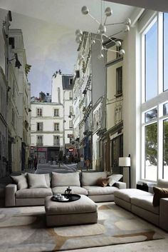 a living room filled with lots of furniture and large window overlooking an alleyway full of buildings