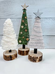 three small christmas trees sitting on top of wooden logs