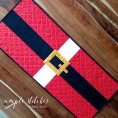 a red, white and black quilted placemat on a wooden floor