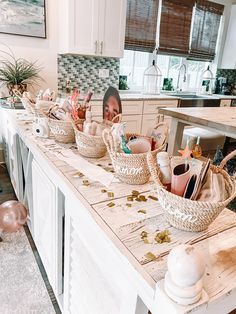 a woman sitting at a kitchen counter with baskets on top of it and other items in front of her