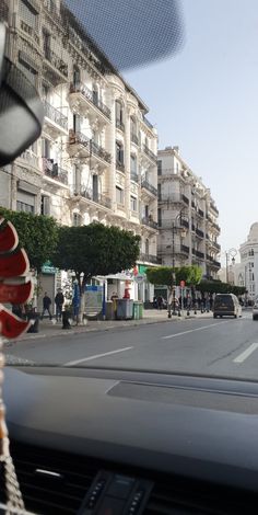 the dashboard of a car on a city street with buildings in the background and people walking around