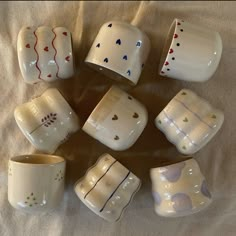 a group of ceramic cups sitting on top of a bed