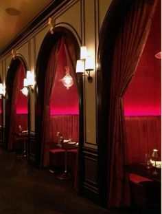 the interior of a restaurant with red walls and curtains on either side of the tables