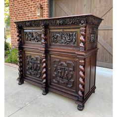 an ornately carved wooden cabinet in front of a brick building with a garage door