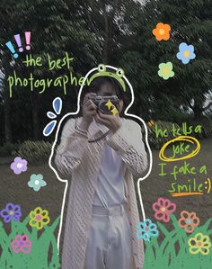 a person taking a photo with a camera in front of flowers and trees, while holding a frog