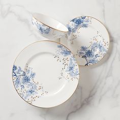 two blue and white plates sitting on top of a marble countertop next to each other