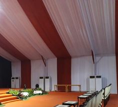 an empty stage set up with white chairs and flowers on the floor in front of it