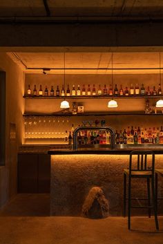 a dimly lit bar with stools and bottles on the shelves