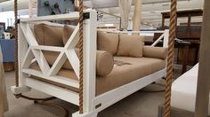 a white swing bed with tan cushions in a room filled with furniture and other items