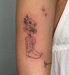 a small tattoo on the arm of a woman with flowers in a cowboy boot and stars