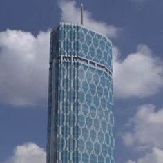 a tall blue building with white designs on it's side and clouds in the background