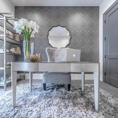 a desk with a laptop on top of it in front of a mirror and shelves