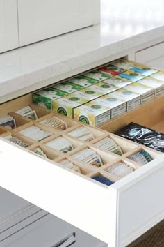 an open drawer in a kitchen filled with lots of papers and other items on the counter