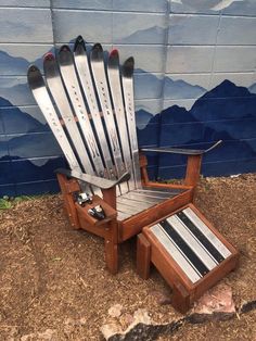 a chair made out of skis sitting on the ground next to a wall with mountains painted on it