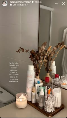 a bathroom counter with various items on it and a candle in front of the mirror