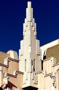 a tall white building with statues on it's sides against a clear blue sky