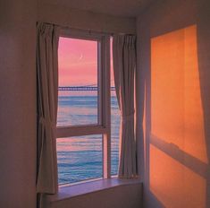 the sun is setting over the ocean from an empty room with a window overlooking the water