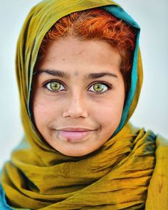 a young woman with red hair and green scarf on her head looking at the camera