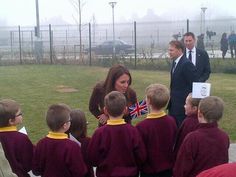 the young children are standing in front of the man talking to them and one is wearing a suit