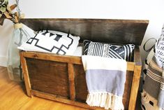 a wooden bench with pillows and blankets on it