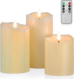 three lit candles with remote control on white background