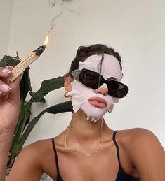 a woman holding a match stick and wearing a mask