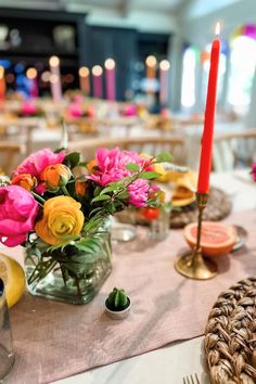 the table is set with flowers and candles in vases, plates, and napkins