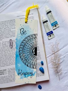 an open book with the words be happy on it next to some markers and pens