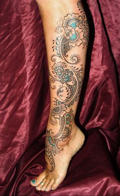 a woman's foot with an intricate tattoo on her leg and the bottom part of her arm