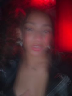 a blurry photo of a woman's face in the dark with red lights behind her