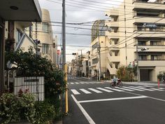 an empty city street with buildings on both sides and people riding bikes in the middle