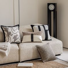 a living room with a couch, pillows and a clock on the wall behind it