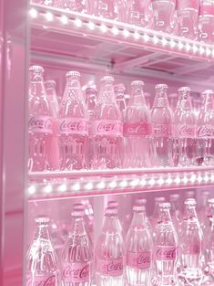 many pink coca - cola bottles are lined up on shelves