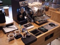 a coffee machine sitting on top of a wooden counter next to cups and saucers