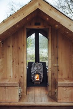 a wood burning stove in the middle of a wooden structure with benches around it and lights on