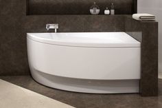 a white bath tub sitting in a bathroom next to a sink and toilet paper dispenser