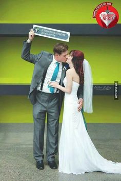 a bride and groom kissing in front of a green wall with the word love written on it