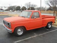 an orange pick up truck parked in a parking lot