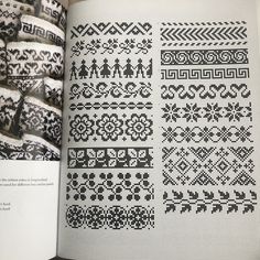 an open book with black and white cross stitch designs on the pages, in front of it