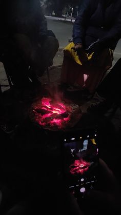 a person is cooking something on a grill in the dark with bright red lights coming from it